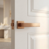 Pina on Square Rosette elegant square internal door handles in a unique brushed PVD copper finish, installed on a bright white paneled door.