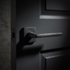 Pyrola on Square Rosette understated square door handles in a sleek matt black finish, providing a modern contrast on a dark grey door.