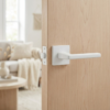 Understated square door handles in a clean matt white finish from the Pyrola collection, installed on a light natural wood door.