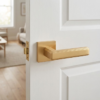 High-end square door handles in a soft matt gold finish from the Raflesia range, providing a sophisticated look on a classic white paneled door.