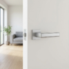 Sleek satin chrome Raflesia on Square Rosette high-end square door handles with a smooth brushed texture, installed on a minimalist white interior door.