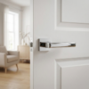 Stylish square internal door handles in a mirror-finish polished chrome from the Salice range, mounted on a bright white paneled door.