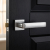 Sophisticated square door handles in a sleek satin chrome finish from the Stella on Square Rosette collection, installed on a contemporary black interior door.