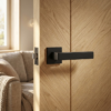 Bold matt black Sulla on Square Rosette sleek square internal door handles providing a sharp, modern contrast on a natural oak wood door.