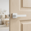 Sulla on Square Rosette sleek square internal door handles in a clean matt white finish, mounted on a light natural wood door for a bright, modern look.
