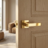Sleek square internal door handles in a brilliant PVD gold finish from the Sulla range, installed on a classic oak timber door.