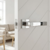 High-shine polished chrome Sulla on Square Rosette sleek square internal door handles featuring a reflective mirror finish on a white chevron-patterned door.