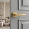 Contemporary satin gold Sulla on Square Rosette sleek square internal door handles with a soft brushed texture on a sophisticated grey door.