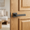 Contemporary square door handles in a sleek matt anthracite finish from the Tilia collection, installed on a natural oak wood door.