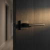 Yuka on Square Rosette sleek square internal door handles in a bold matt black finish, providing a modern accent on a dark timber door.