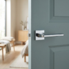 Yuka on Square Rosette sleek square internal door handles in a mirror-like polished chrome finish, mounted on a contemporary blue-grey door.