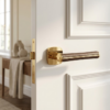 Luxurious polished gold and brown leather Davidia refined internal door handles mounted on a classic white interior door.