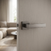 Designer square door handles in a dark metallic graphite finish from the Alisso on Square Rosette range, installed on a light grey wood grain door.