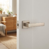 Elegant satin nickel Alisso on Square Rosette designer square door handles with a warm, soft metallic glow on a classic white door.