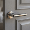 Asteria on Round Rosette in polished chrome, a reflective versatile classic door handle fitted to a grey internal door.