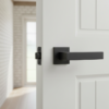Bold internal door handles in matt black, displaying the Erica lever on a square rosette installed on a white internal door with strong contemporary styling.