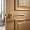 Sleek curved door handle in matt gold finish, Euphorbia on Round Rosette, styled on a natural oak internal door.