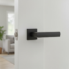 Contemporary square internal door handles in matt black, showcasing the Fresia lever with a square rosette on a sleek white internal door.