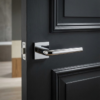 Minimalist square door handles showcasing the Funkia lever on a square rosette in polished chrome, installed on a dark internal door for striking contrast.