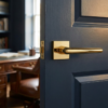 Jasmina on Square Rosette minimalist square internal door handles in polished gold, installed on a deep blue door to create a refined contrast in a modern home office setting.