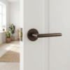 Brown Kalmia on Round Rosette shown fitted to a white door, highlighting its sleek round internal door handle design in a modern, bright interior.