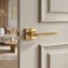 High-shine polished gold Lila on Square Rosette minimalist square internal door handles installed on a classic white panelled door.