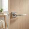Elegant satin nickel Lila on Square Rosette minimalist square internal door handles with a warm metallic undertone on a pale timber door.
