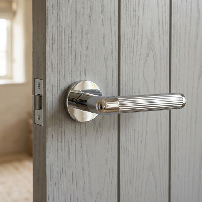 Lobelia - Polished Chrome Lobelia on Round Rosette in polished chrome, showcasing modern round internal door handles on a light grey vertical-panel door.
