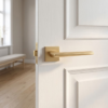 Contemporary matt gold Lunaria on Square Rosette premium square internal handles with a soft brushed texture on a classic white door.