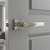 Highly reflective polished chrome Mela on Square Rosette timeless square internal door handles featuring a mirror-like shine on a light grey paneled door.