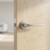 Satin chrome Oleandro on Round Rosette mounted on a natural oak door, highlighting the subtle brushed texture of these versatile round internal door handles.