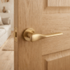 Matt gold Orchide on Round Rosette fitted to an oak door, featuring elegant curved door handles for modern interiors.