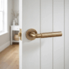 Ficaria on Round Rosette in antique patina, featuring elegant brass door handles on a white interior door.